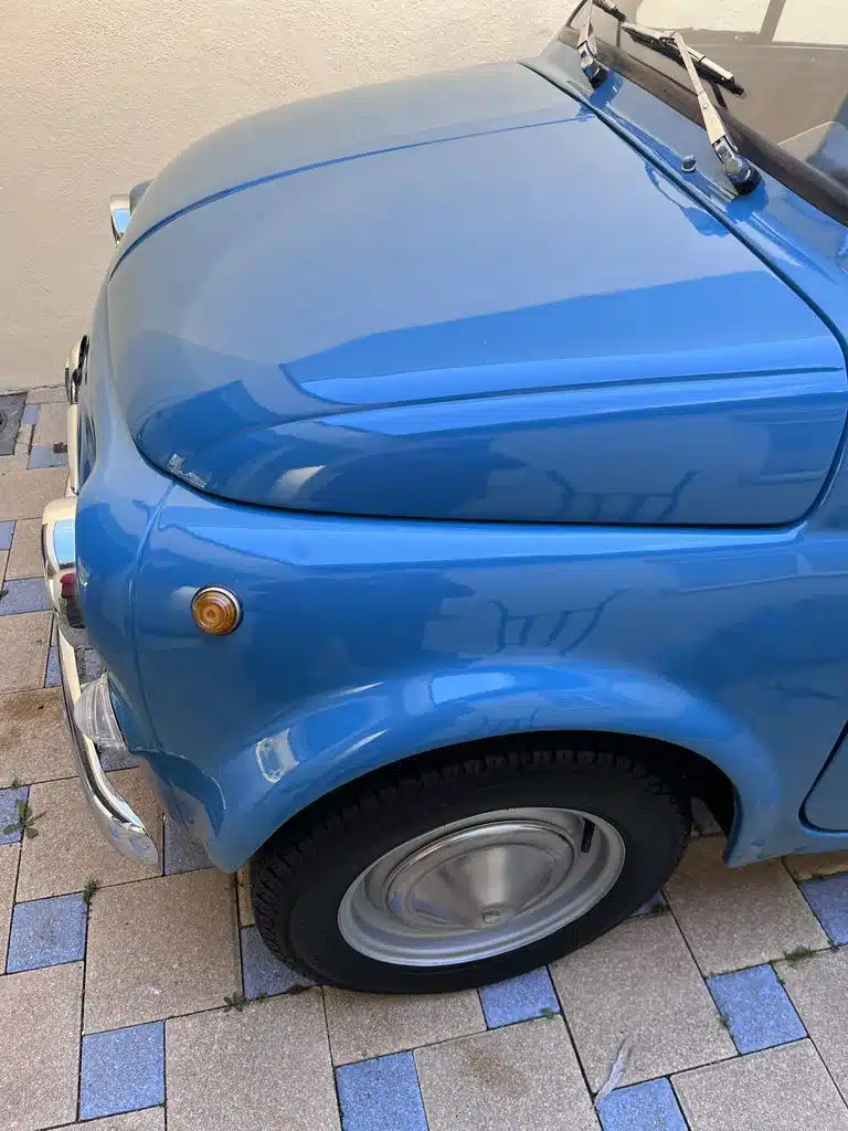 Nahaufnahme der blauen Frontpartie eines klassischen Fiat 500L mit Rad und Scheinwerfer.
