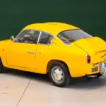 Fiat Abarth 750 Zagato, Baujahr 1958, gelb lackiert, restauriert, mit Double-Bubble-Dach, Seiten- und Heckansicht, aufgenommen in einer Halle.