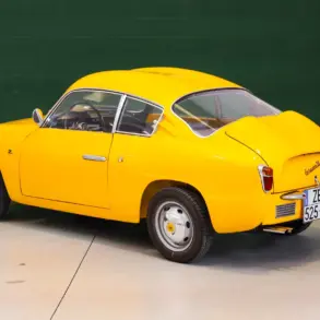 Fiat Abarth 750 Zagato, Baujahr 1958, gelb lackiert, restauriert, mit Double-Bubble-Dach, Seiten- und Heckansicht, aufgenommen in einer Halle.