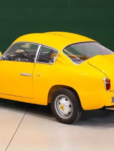 Fiat Abarth 750 Zagato, Baujahr 1958, gelb lackiert, restauriert, mit Double-Bubble-Dach, Seiten- und Heckansicht, aufgenommen in einer Halle.