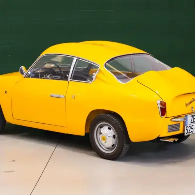 Fiat Abarth 750 Zagato, Baujahr 1958, gelb lackiert, restauriert, mit Double-Bubble-Dach, Seiten- und Heckansicht, aufgenommen in einer Halle.