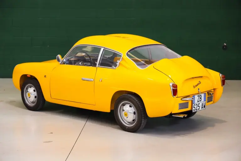 Fiat Abarth 750 Zagato, Baujahr 1958, gelb lackiert, restauriert, mit Double-Bubble-Dach, Seiten- und Heckansicht, aufgenommen in einer Halle.