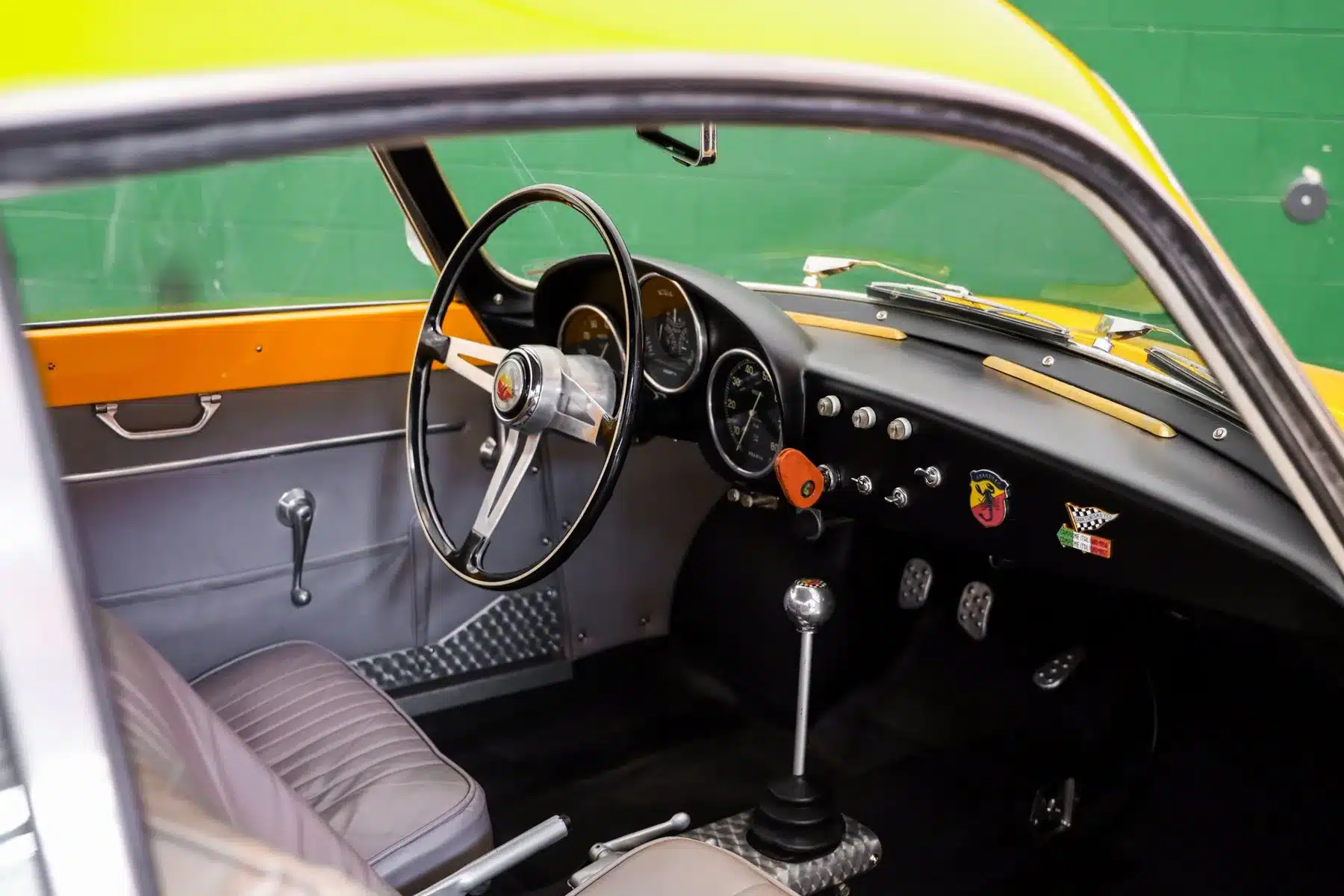 Innenansicht des Cockpits eines restaurierten Fiat Abarth 750 Zagato, Baujahr 1958, mit Lenkrad, Schalthebel und Armaturenbrett.