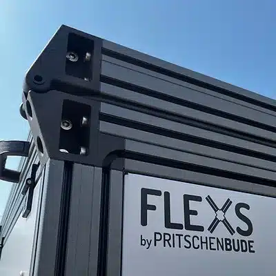 Ecke und Profilkonstruktion des FLEXS-Modulsystems für Pritschenfahrzeuge, Herstellerlogo sichtbar