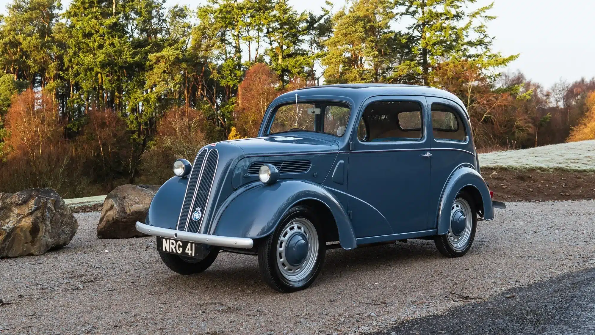 Ford Popular 103E von 1959 in Richmond Blue vor Bäumen und Felsen, restaurierter Zustand