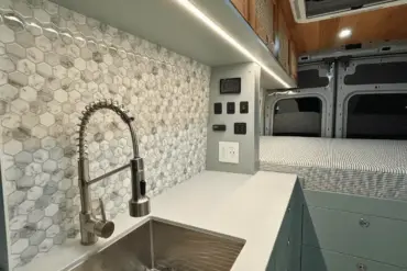 Küchenzeile mit Edelstahlspüle, Wasserhahn und danebenliegendem Stauraum im Ford Transit Bon Echo Campervan
