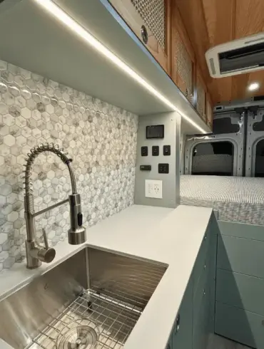 Küchenzeile mit Edelstahlspüle, Wasserhahn und danebenliegendem Stauraum im Ford Transit Bon Echo Campervan