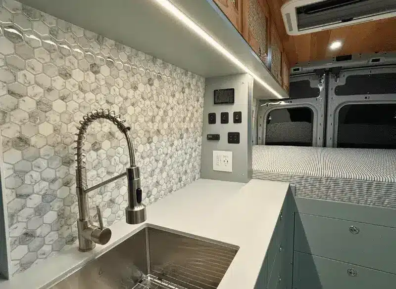 Küchenzeile mit Edelstahlspüle, Wasserhahn und danebenliegendem Stauraum im Ford Transit Bon Echo Campervan