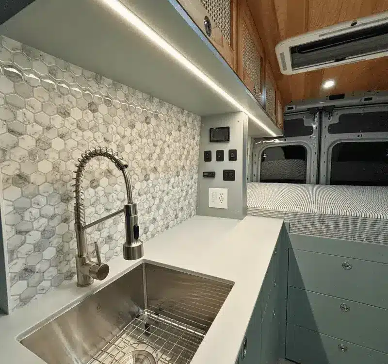 Küchenzeile mit Edelstahlspüle, Wasserhahn und danebenliegendem Stauraum im Ford Transit Bon Echo Campervan
