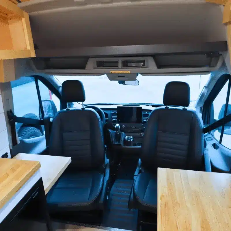 Innenansicht des Ford Transit Campervans mit drehbaren Vordersitzen und Holzarbeitsflächen
