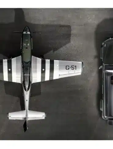 Luftaufnahme eines Mercedes G-Klasse Geländewagens neben einem North American P-51 Mustang Flugzeug, beide mit abgestimmtem Design.