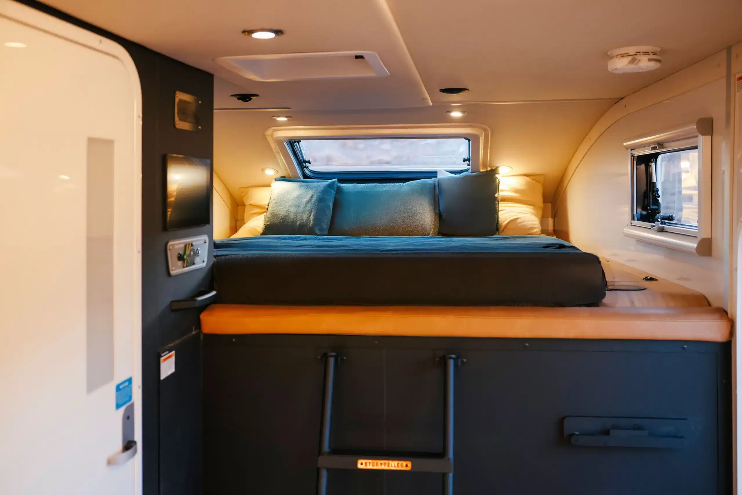 Schlafbereich im GXV HILT Expeditionsmobil mit großzügigem Bett, Polstern und Fenstern.