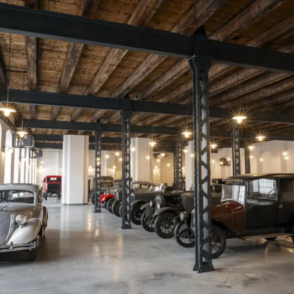 Ausstellung historischer Škoda-Fahrzeuge im Originalzustand in einer restaurierten Fabrikhalle mit sichtbaren Stahlträgern und Holzbalkendecke