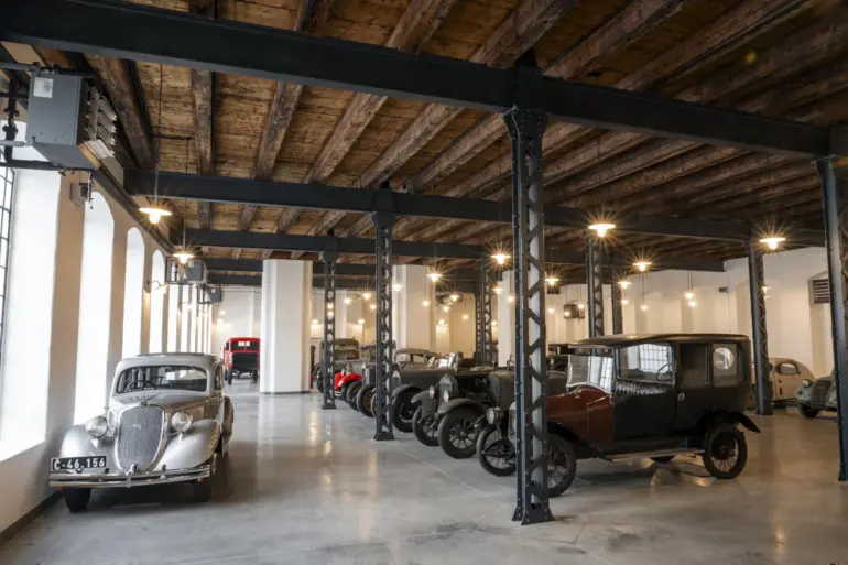 Ausstellung historischer Škoda-Fahrzeuge im Originalzustand in einer restaurierten Fabrikhalle mit sichtbaren Stahlträgern und Holzbalkendecke
