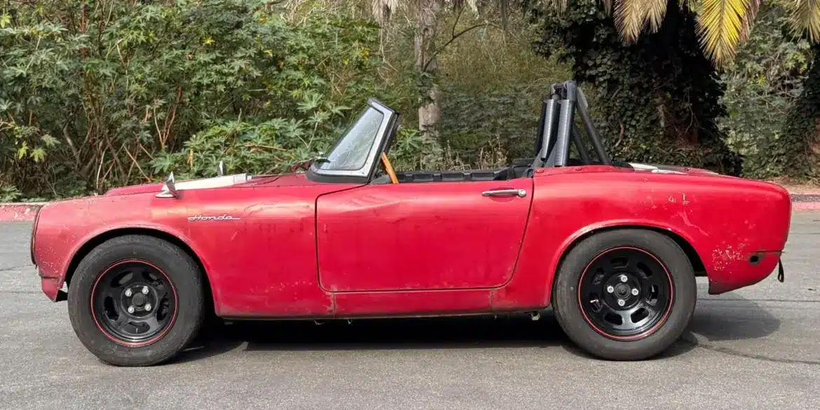 Roter Honda S600 Roadster von 1964 aus der Seitenansicht, unrestauriert, mit sichtbaren Gebrauchsspuren.