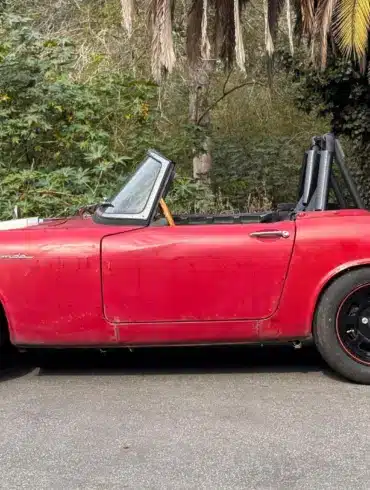 Roter Honda S600 Roadster von 1964 aus der Seitenansicht, unrestauriert, mit sichtbaren Gebrauchsspuren.