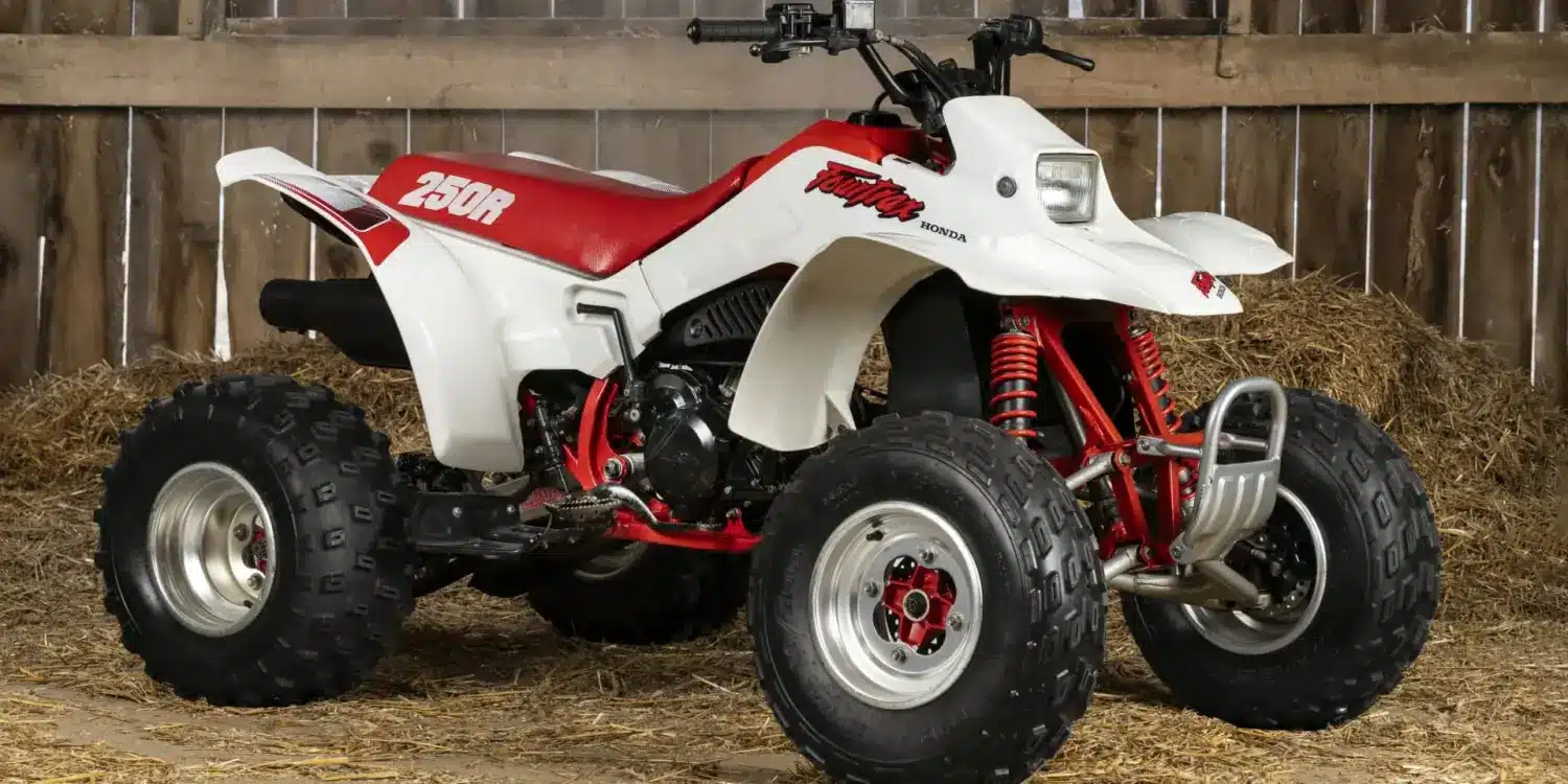 Honda TRX250R Fourtrax 1989, weiß-rot, in einer traditionellen Holzscheune auf Stroh stehend