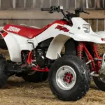 Honda TRX250R Fourtrax 1989, weiß-rot, in einer traditionellen Holzscheune auf Stroh stehend