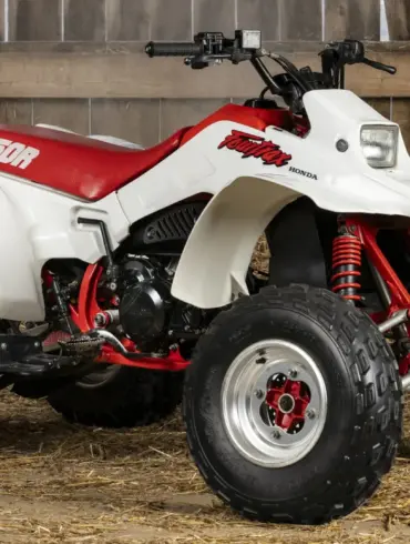 Honda TRX250R Fourtrax 1989, weiß-rot, in einer traditionellen Holzscheune auf Stroh stehend