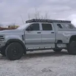 2020 International CV515 Pickup in Nardo-Grau mit Expeditionsausstattung, großen Offroad-Reifen und robusten Anbauteilen auf einem Kiesplatz.