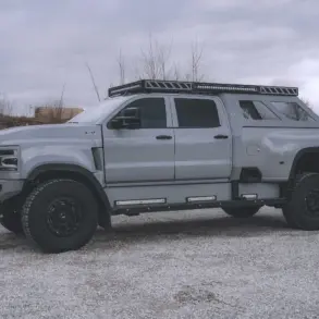 2020 International CV515 Pickup in Nardo-Grau mit Expeditionsausstattung, großen Offroad-Reifen und robusten Anbauteilen auf einem Kiesplatz.
