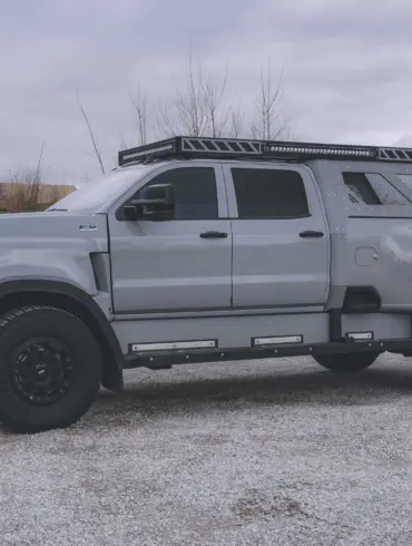 2020 International CV515 Pickup in Nardo-Grau mit Expeditionsausstattung, großen Offroad-Reifen und robusten Anbauteilen auf einem Kiesplatz.