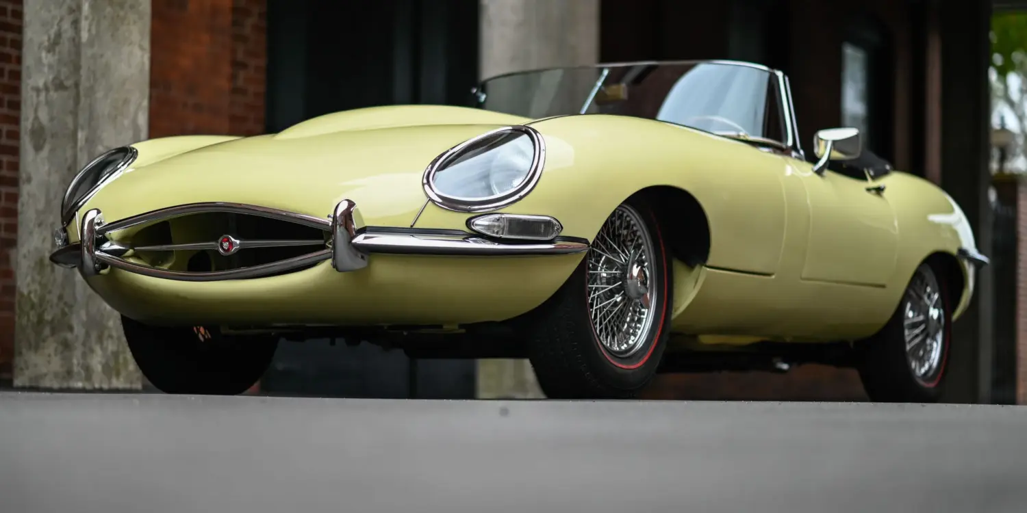 Jaguar E-Type Series 1 Roadster von 1967 in pale primrose gelb mit geöffnetem Verdeck, niedrige Frontansicht.