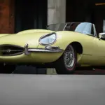 Jaguar E-Type Series 1 Roadster von 1967 in pale primrose gelb mit geöffnetem Verdeck, niedrige Frontansicht.