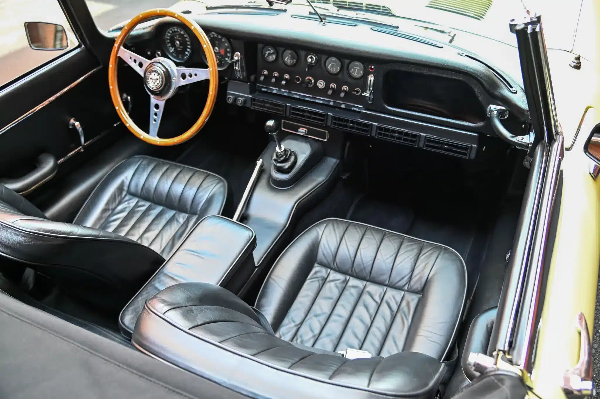 Der Innenraum eines restaurierten Jaguar E-Type Series 1 Roadster von 1967 mit schwarzem Leder, Holzlenkrad und originalgetreuen Instrumenten.