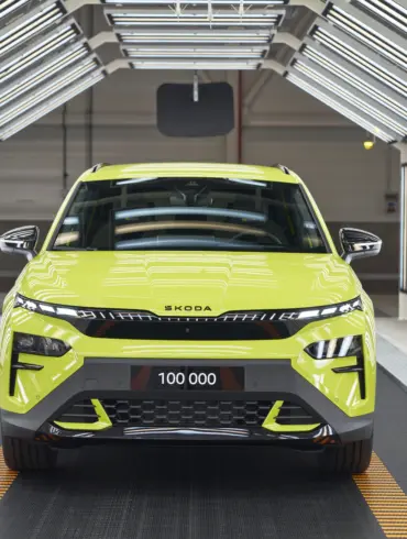 Frontansicht eines Škoda Elroq RS in Mamba Green im Werk unter Fertigungslichtern, Kennzeichen mit 100.000