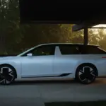 Weißer Škoda Vision O Elektro-Kombi steht seitlich unter einem Carport bei Sonnenuntergang.