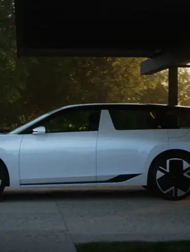 Weißer Škoda Vision O Elektro-Kombi steht seitlich unter einem Carport bei Sonnenuntergang.