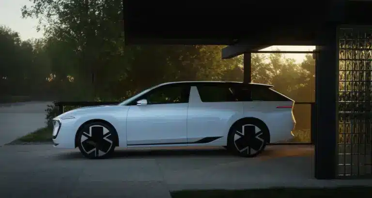 Weißer Škoda Vision O Elektro-Kombi steht seitlich unter einem Carport bei Sonnenuntergang.
