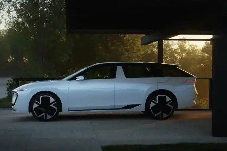 Weißer Škoda Vision O Elektro-Kombi steht seitlich unter einem Carport bei Sonnenuntergang.