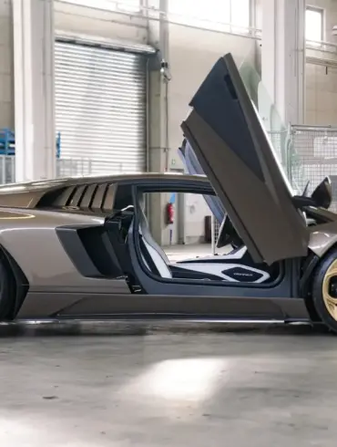 Lamborghini Countach LPI 800-4 in Luci del Bosco, Seitenansicht mit geöffneten Scherentüren und bronzenen Felgen in einer Werkstatthalle.
