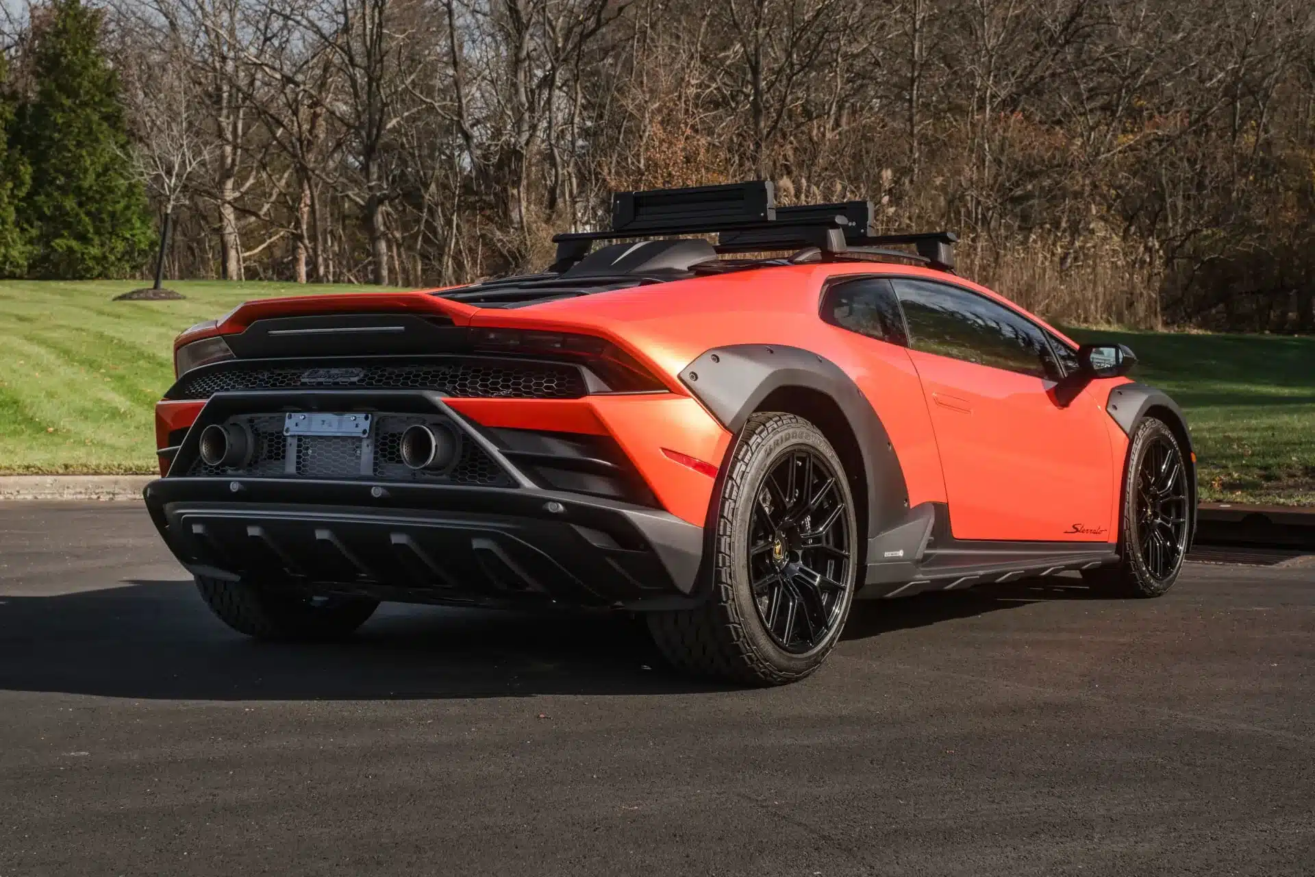 Roter Lamborghini Huracán Sterrato von hinten, mit Offroad-Elementen, auf einer Straße stehend.