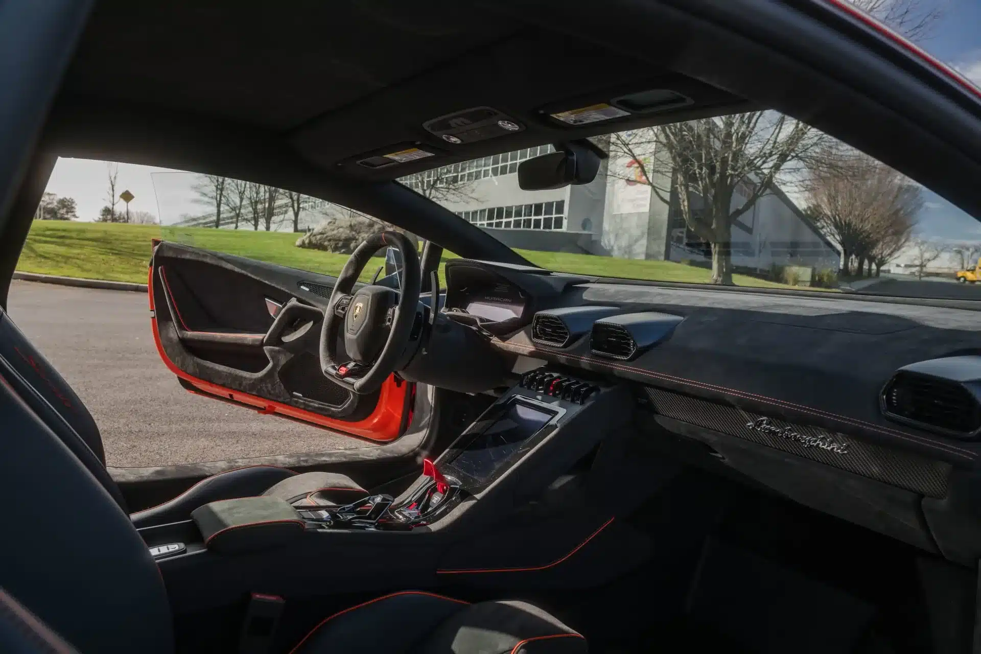 Innenraum eines Lamborghini Huracán Sterrato mit geöffneter Fahrertür, Blick auf das Cockpit und die Fahrersitze