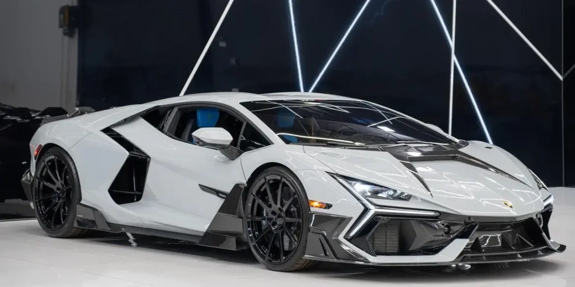 Weißer Lamborghini Revuelto Mansory 2025 mit zahlreichen Carbon-Details in einem modernen Showroom.