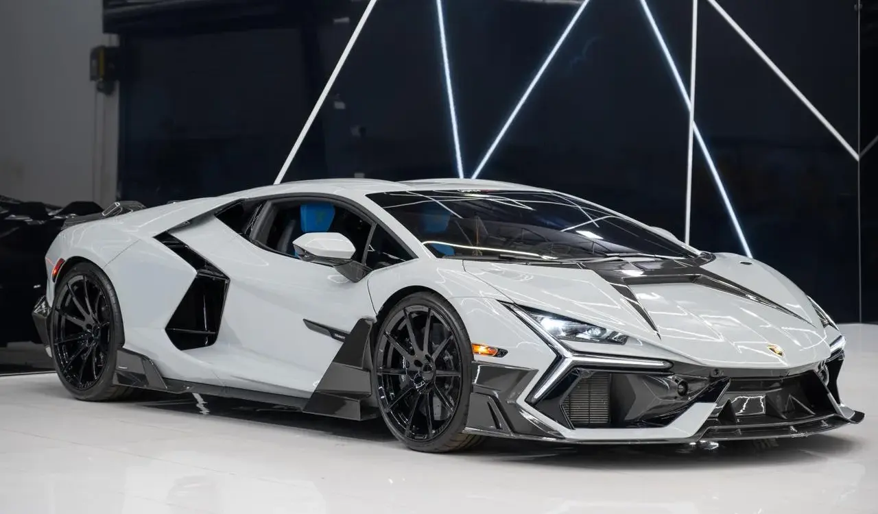 Weißer Lamborghini Revuelto Mansory 2025 mit zahlreichen Carbon-Details in einem modernen Showroom.