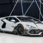 Weißer Lamborghini Revuelto Mansory 2025 mit zahlreichen Carbon-Details in einem modernen Showroom.