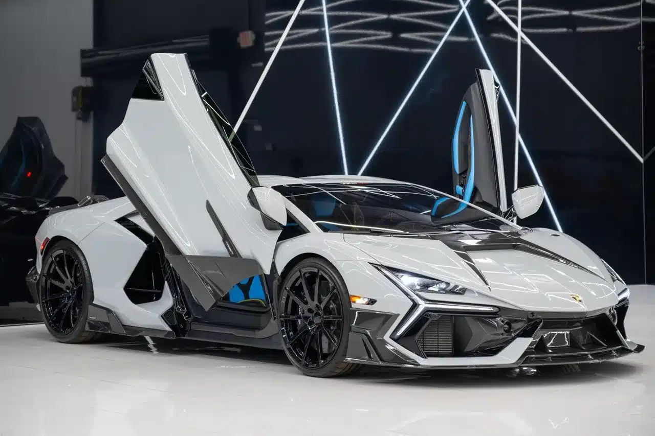 Lamborghini Revuelto Mansory 2025 in Weiß mit Carbon-Elementen und geöffneten Scherentüren in modernem Showroom.