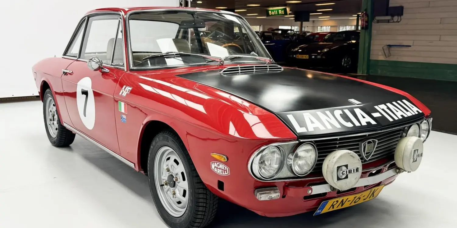 Lancia Fulvia Coupé Rallye 1.3S in Rot mit schwarzer Motorhaube und Zusatzscheinwerfern im Ausstellungsraum.