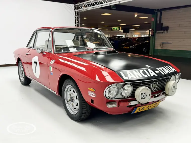 Lancia Fulvia Coupé Rallye 1.3S in Rot mit schwarzer Motorhaube und Zusatzscheinwerfern im Ausstellungsraum.