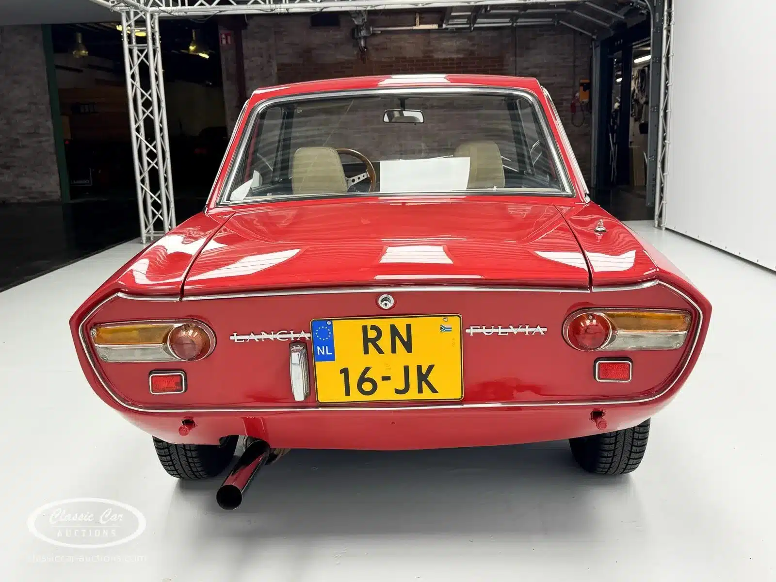 Rotes Lancia Fulvia Coupé Rallye 1.3S (Baujahr 1974) von hinten mit gelbem holländischen Kennzeichen in einer Indoor-Lokation.