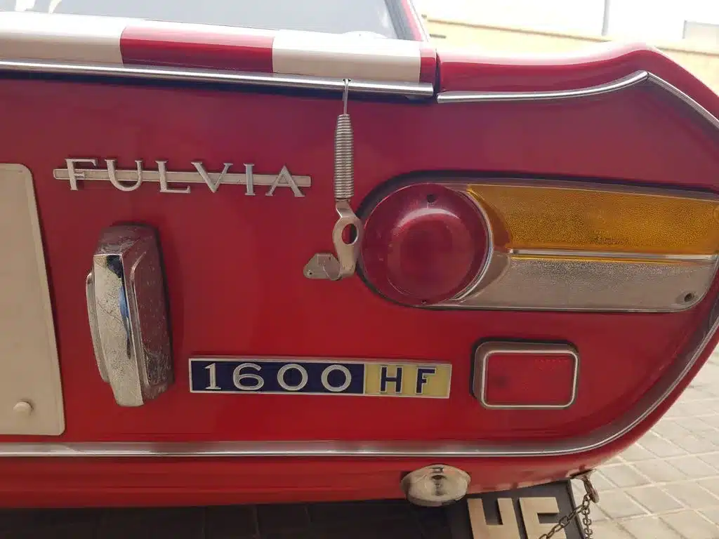 Heckpartie einer roten Lancia Fulvia 1600 HF mit Typenschild, Rückleuchten und Rennsportdetails