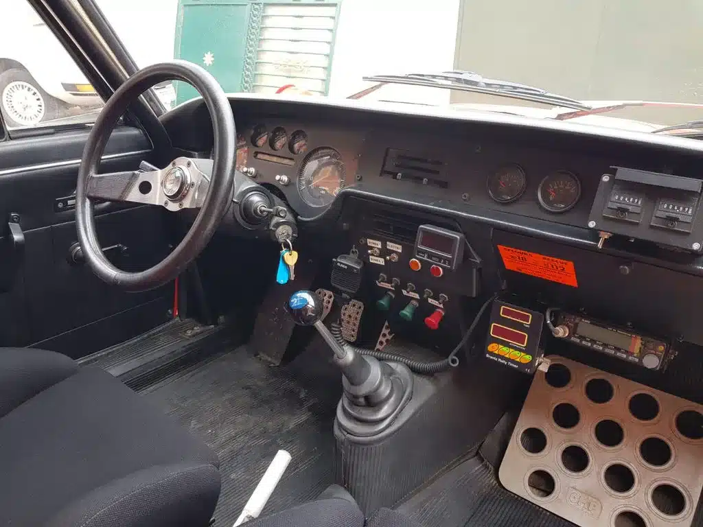 Blick ins Cockpit einer Lancia Fulvia HF 1600 Corsa mit Rennsportlenkrad, Schalthebel, Zusatzinstrumenten und Rallyeschaltern