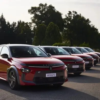 Mehrere Lancia Ypsilon HF in Rot-Schwarz stehen nebeneinander auf einer Straße vor Bäumen.