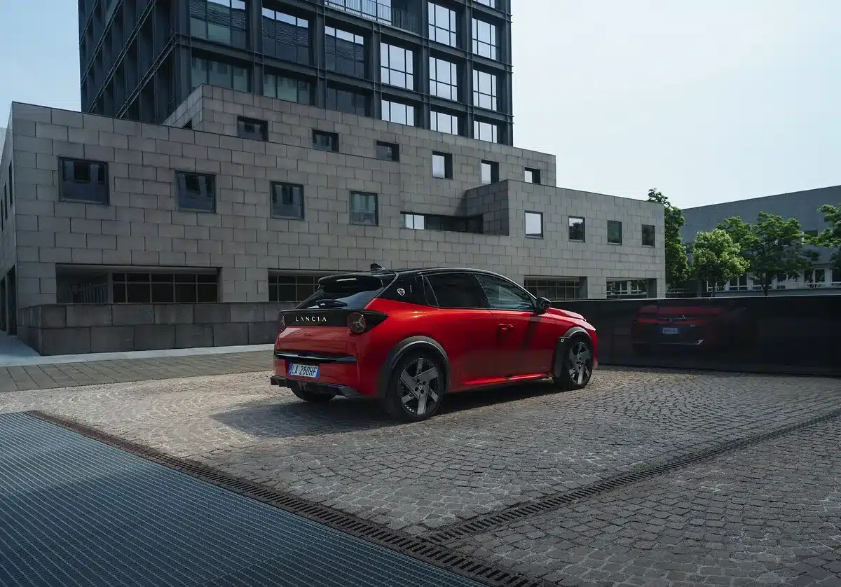 Lancia Ypsilon HF, rot-schwarz, sportliche Kompaktlimousine, von hinten und der Seite vor einem modernen Gebäude