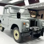 Restaurierter Land Rover Series II Baujahr 1968 mit grauer Lackierung und Kennzeichen XN-81-14, frontal aufgenommen in einer Ausstellungshalle.