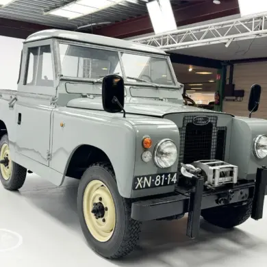 Restaurierter Land Rover Series II Baujahr 1968 mit grauer Lackierung und Kennzeichen XN-81-14, frontal aufgenommen in einer Ausstellungshalle.